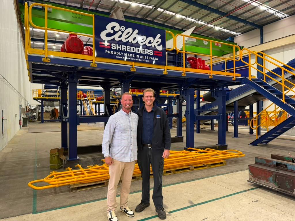 Two people stand in front of the finished shredding line in the Ingleburn workshop