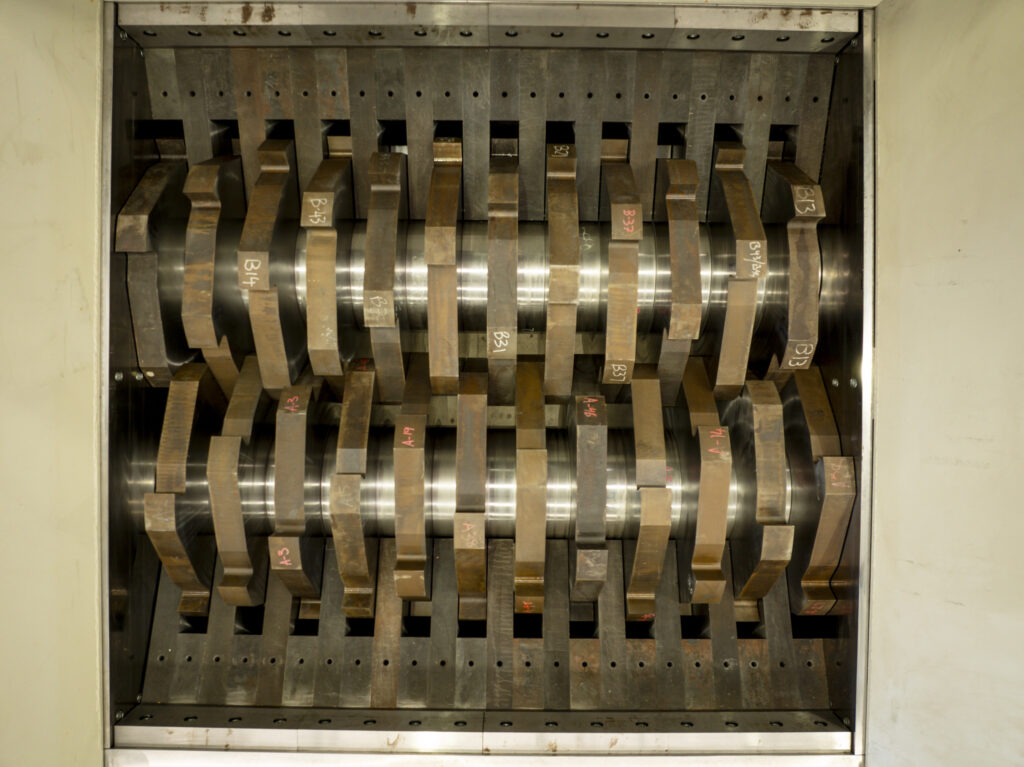 The interlocking cutters of a dual-shaft shredder, seen through the feed opening