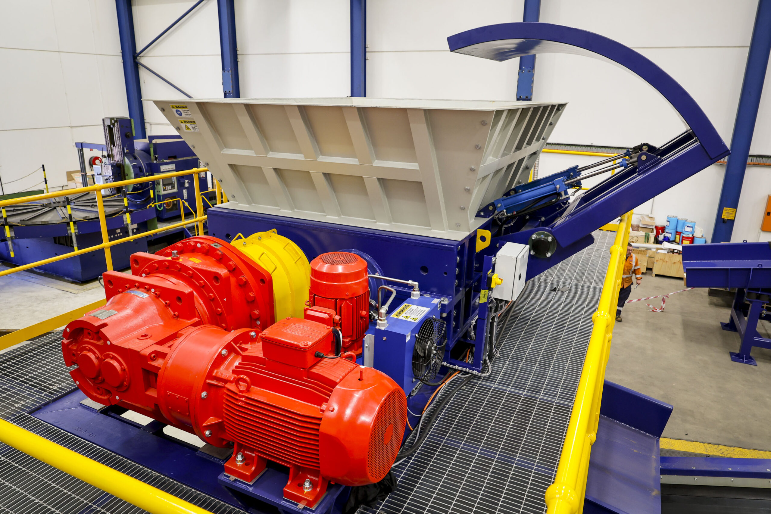 A blue dual-shaft shredder with red drives on the workshop floor