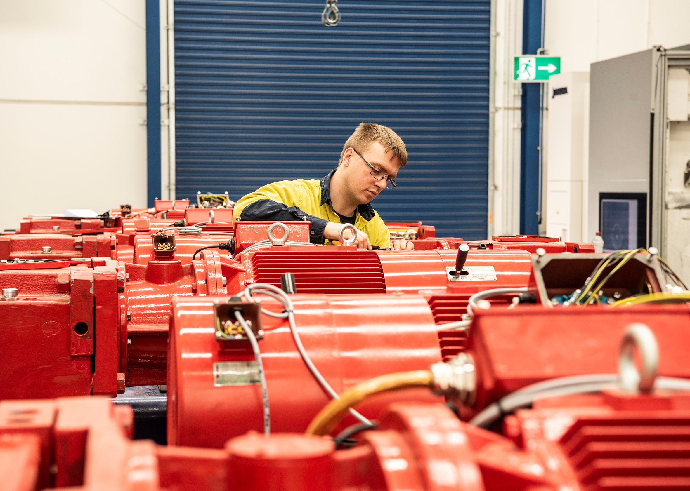An Eilbeck technician works on a row of red electric motors and gearboxes in the workshop