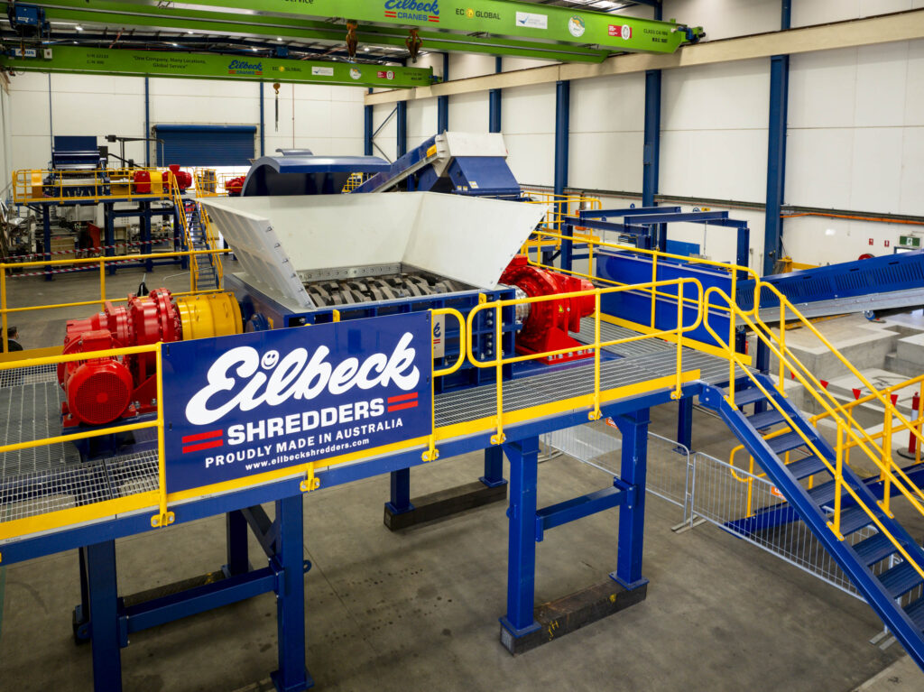 An installed Eilbeck primary shredder on a blue platform under an Eilbeck Shredders banner