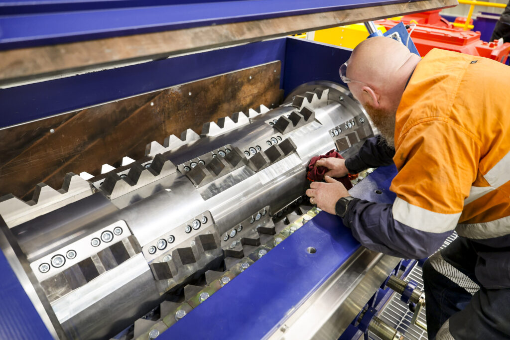 A technician in hi-vis cleaning the knife rotor of an Eilbeck rasper, its lid raised